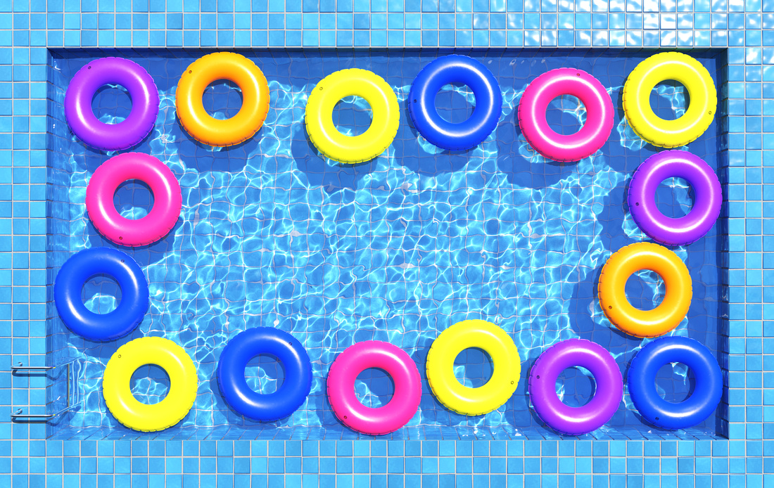Multi-colored swimming rings in swimming pool. Pool party, summer background. Top view